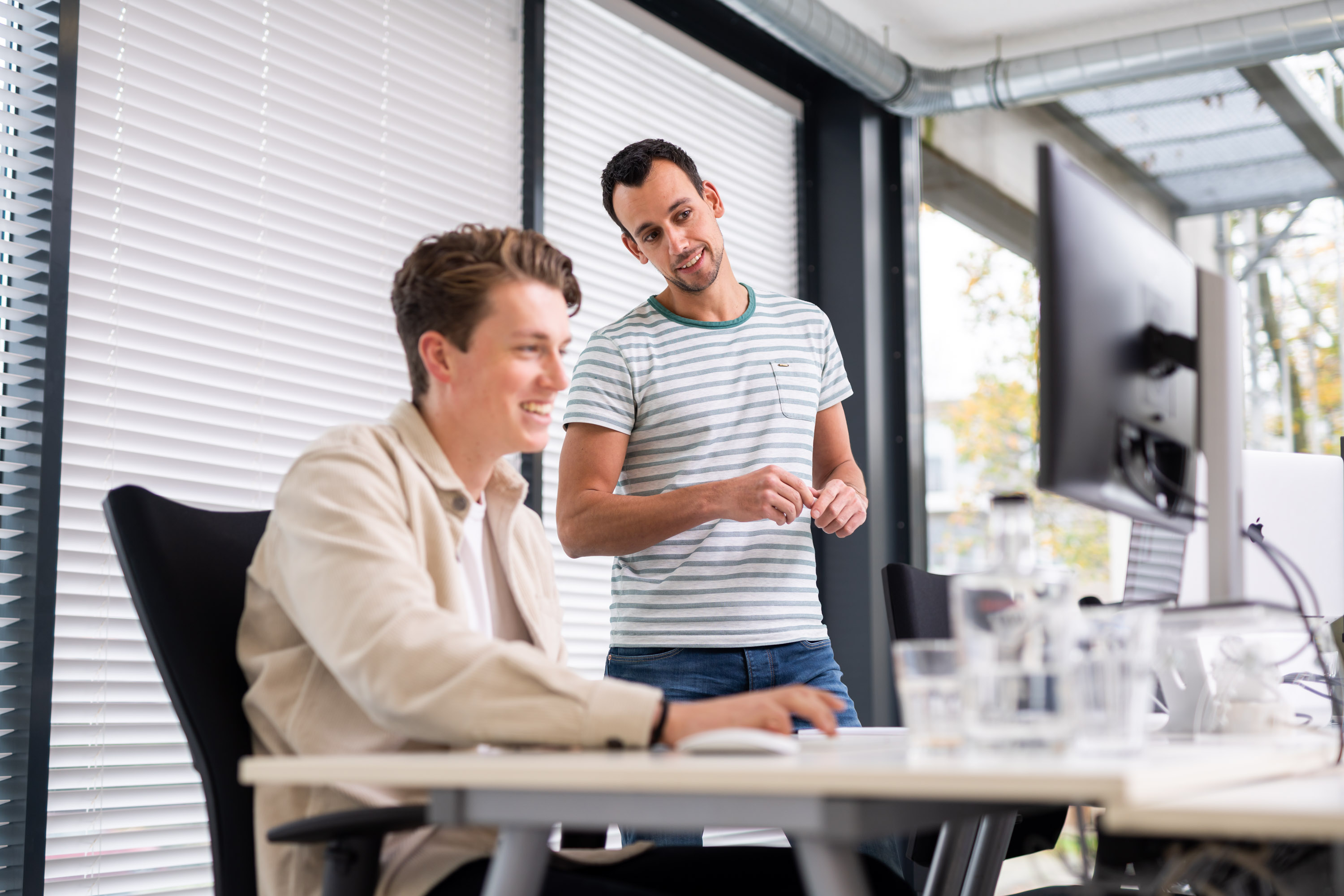 Twee collega's bespreken een bericht op het intranet bij Netvlies